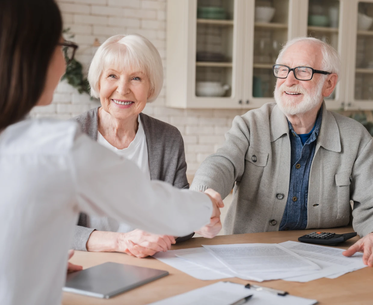 Elderly couple shaking hands with advisor